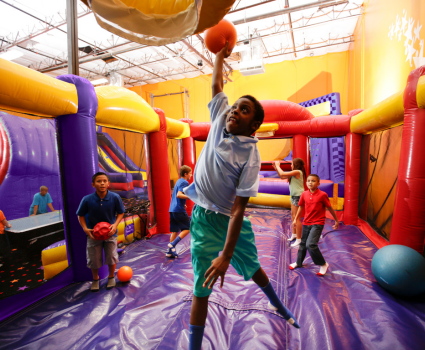 kids running on and playing basketball on inflatable at kids birthday party venue