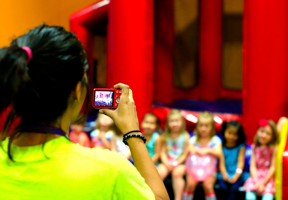 BounceU team member taking party pictures of birthday kid and guests.